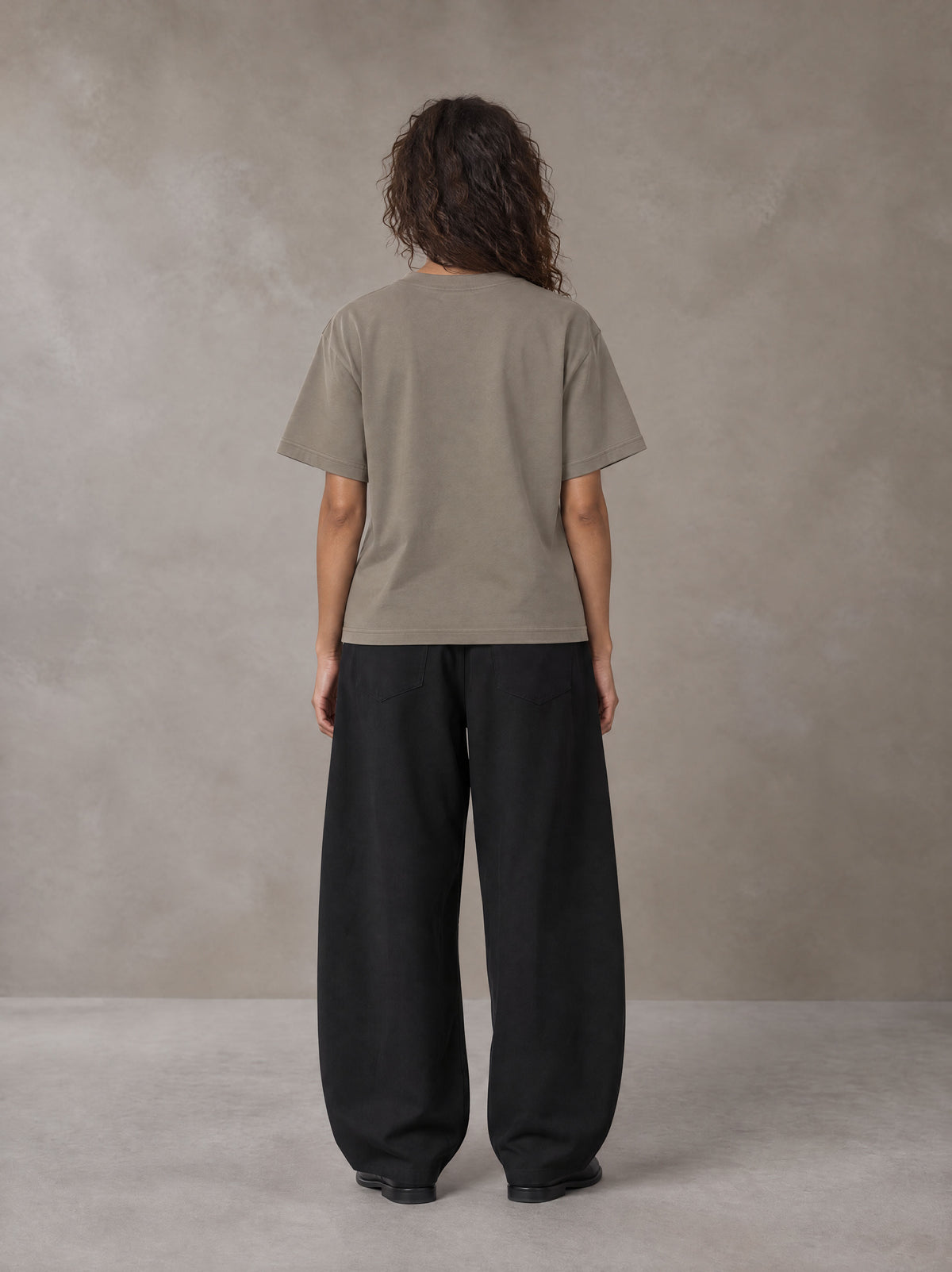 Model wearing SM Sig. Earth T-shirt in Camel Tan, rear view.