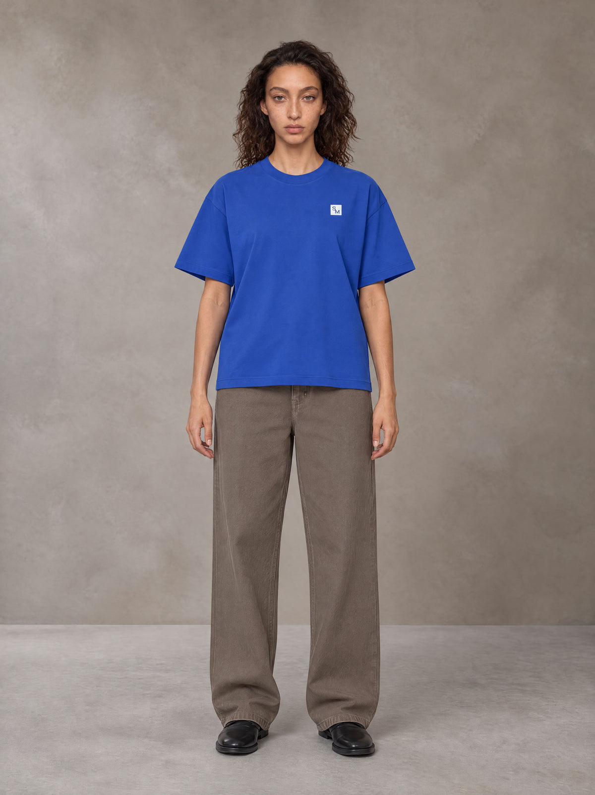 Model wearing SM Sig. Earth T-shirt in Classic Blue, front view.