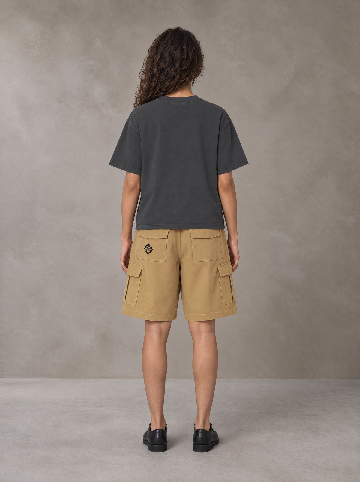Model wearing SM Sig. Earth T-shirt in Deep Charcoal, rear view.