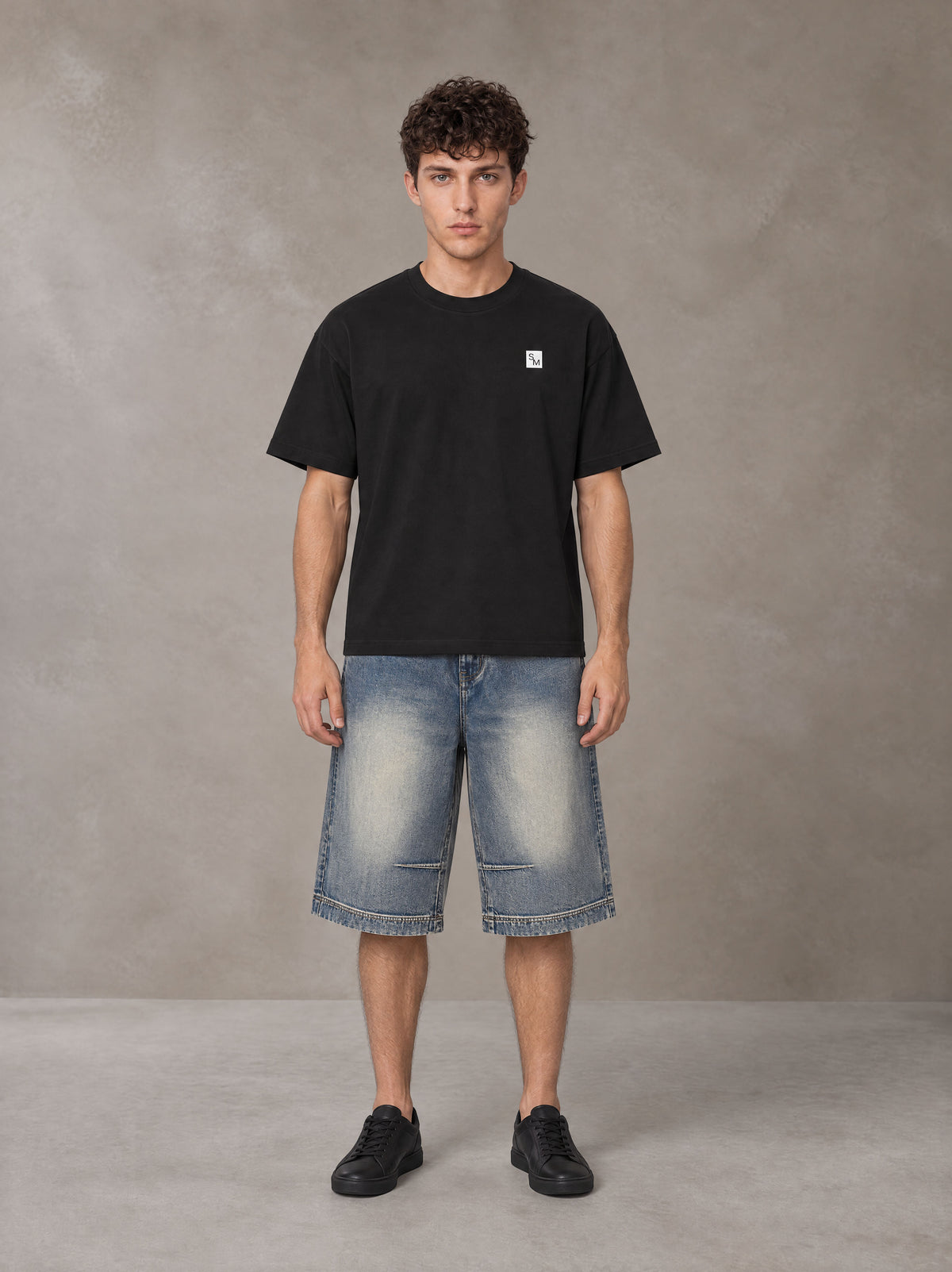 Model wearing SM Sig. Earth T-shirt in Midnight Black, front view.