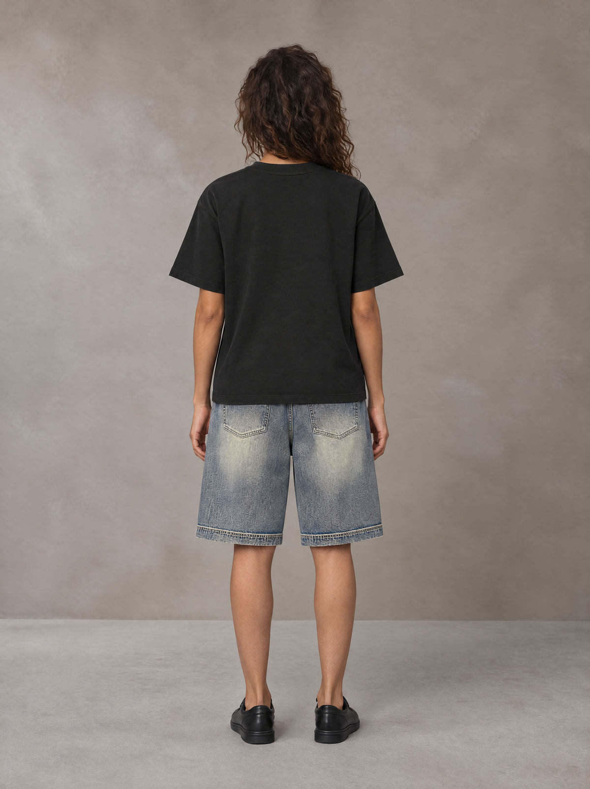 Model wearing SM Sig. Earth T-shirt in Midnight Black, rear view.