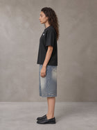 Model wearing SM Sig. Earth T-shirt in Midnight Black, side profile.