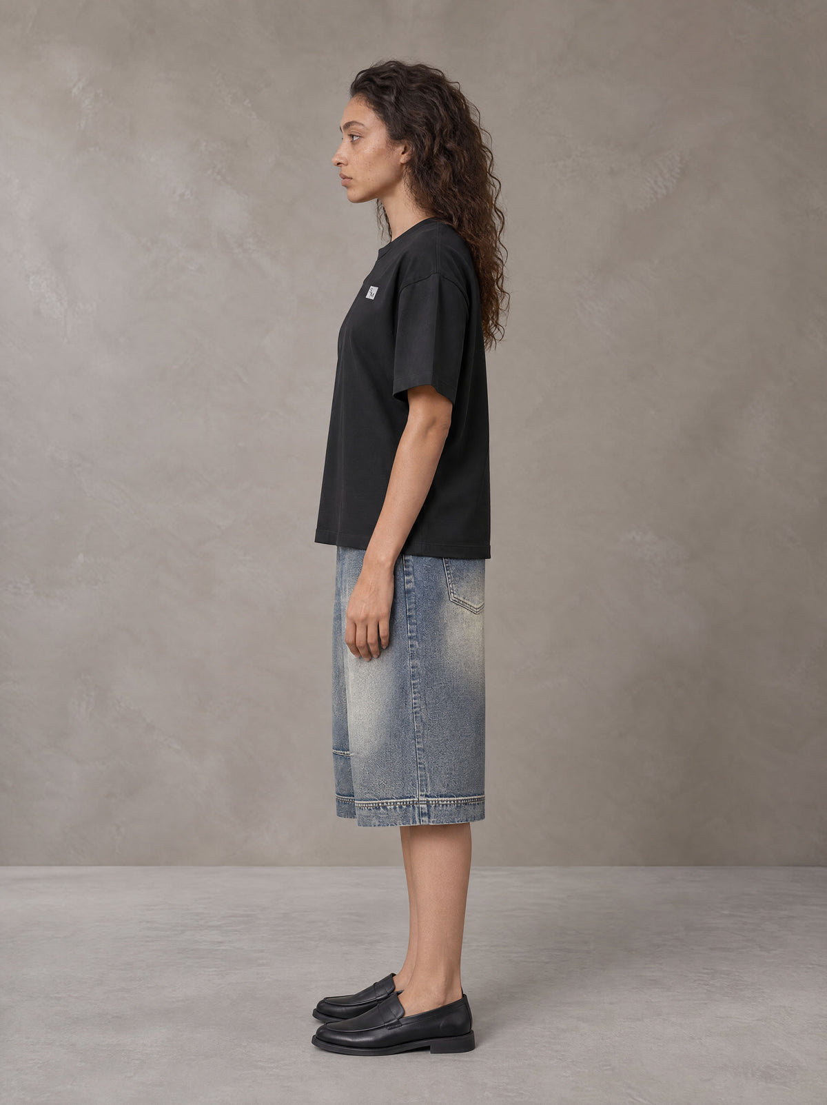 Model wearing SM Sig. Earth T-shirt in Midnight Black, side profile.