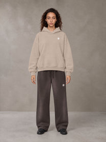 Model wearing SM Sig. Fleece Hoodie in Apricot Grey, front view.