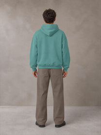 Model wearing SM Sig. Fleece Hoodie in Classic Green, rear view.