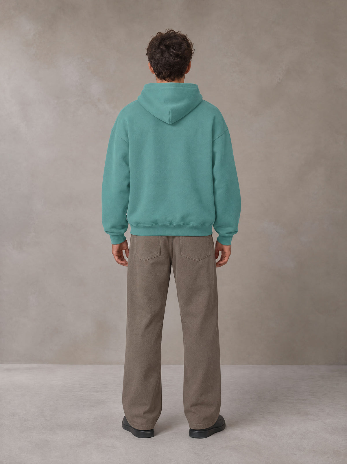 Model wearing SM Sig. Fleece Hoodie in Classic Green, rear view.