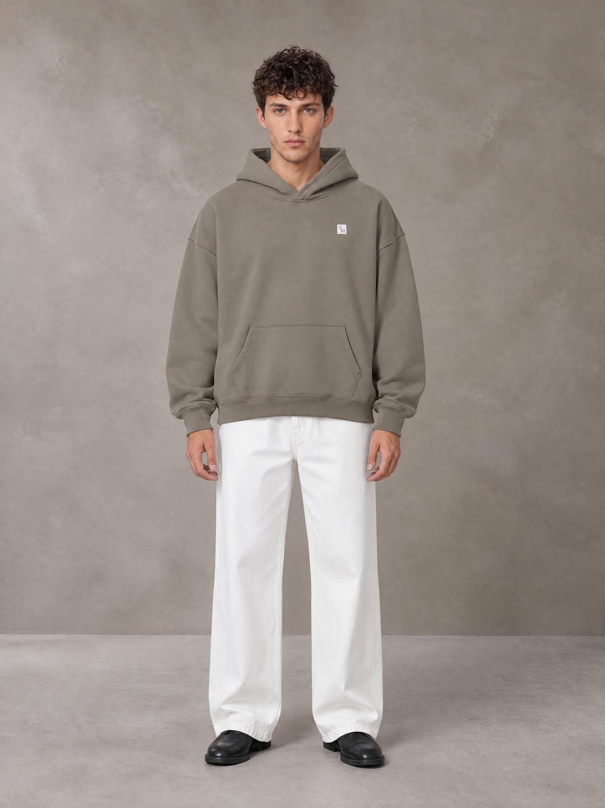 Model wearing SM Sig. Fleece Hoodie in Coffee Grey, front view.