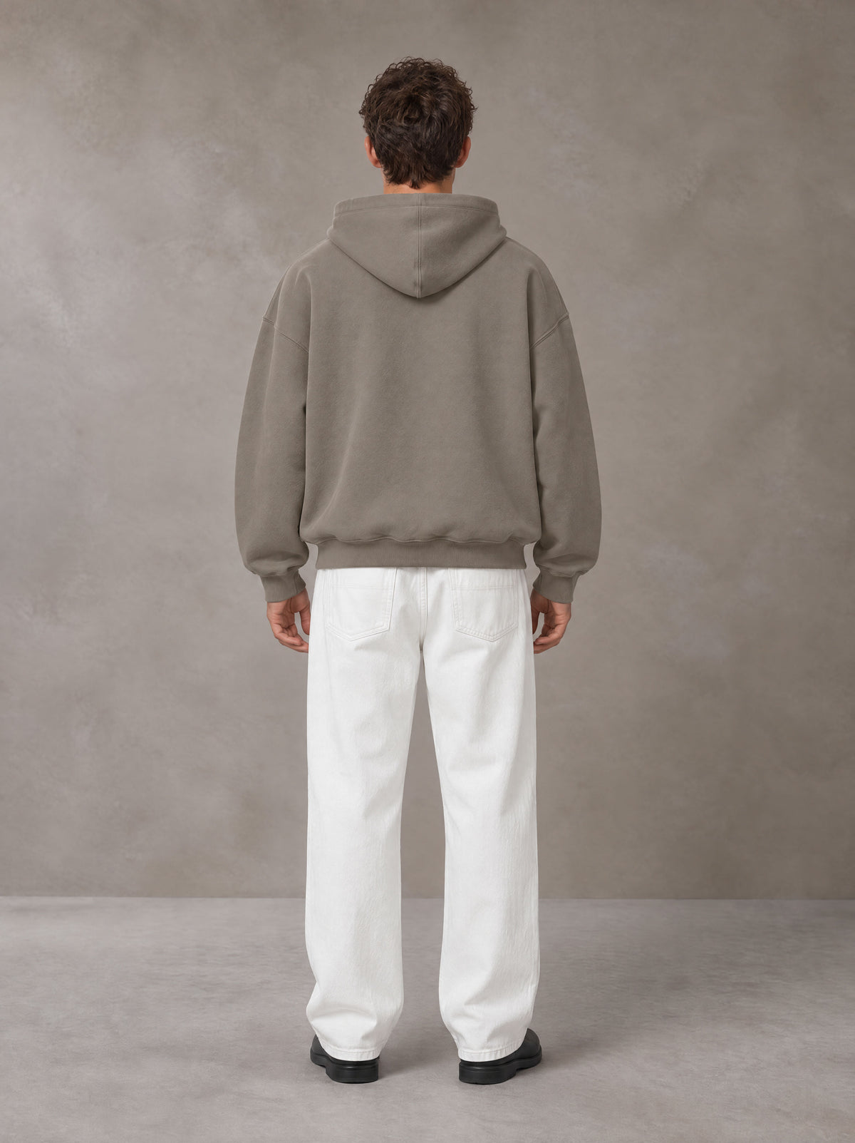 Model wearing SM Sig. Fleece Hoodie in Coffee Grey, rear view.