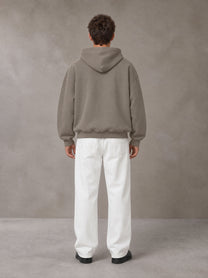 Model wearing SM Sig. Fleece Hoodie in Coffee Grey, rear view.