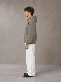 Model wearing SM Sig. Fleece Hoodie in Coffee Grey, side profile.