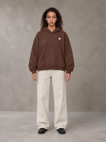 Model wearing SM Sig. Fleece Hoodie in Deep Coffee, front view.