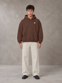 Model wearing SM Sig. Fleece Hoodie in Deep Coffee, front view.