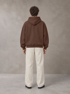 Model wearing SM Sig. Fleece Hoodie in Deep Coffee, rear view.