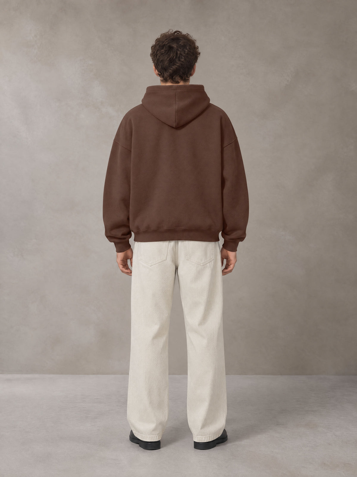 Model wearing SM Sig. Fleece Hoodie in Deep Coffee, rear view.