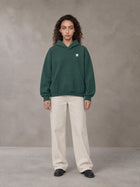 Model wearing SM Sig. Fleece Hoodie in Eden Green, front view.