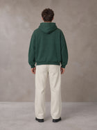 Model wearing SM Sig. Fleece Hoodie in Eden Green, rear view.