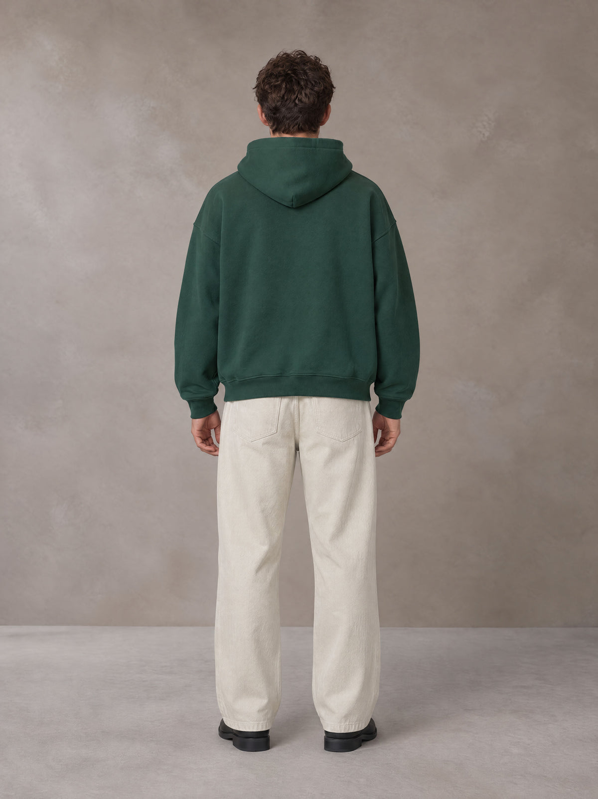 Model wearing SM Sig. Fleece Hoodie in Eden Green, rear view.