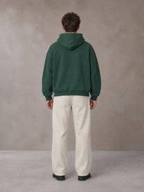 Model wearing SM Sig. Fleece Hoodie in Eden Green, rear view.