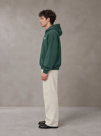 Model wearing SM Sig. Fleece Hoodie in Eden Green, side profile.