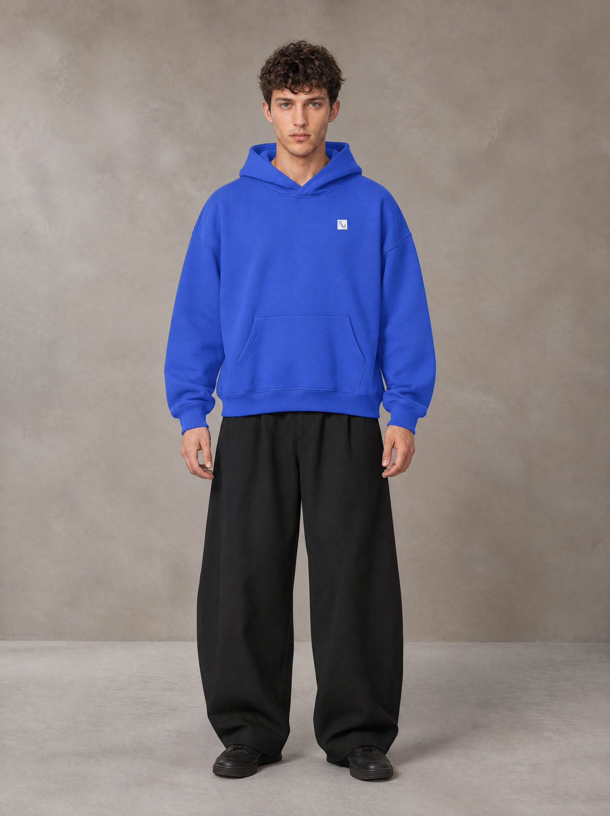 Model wearing SM Sig. Fleece Hoodie in Klein Blue, front view.