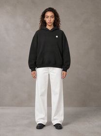Model wearing SM Sig. Fleece Hoodie in Midnight Black, front view.