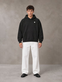 Model wearing SM Sig. Fleece Hoodie in Midnight Black, front view.