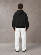 Model wearing SM Sig. Fleece Hoodie in Midnight Black, rear view.