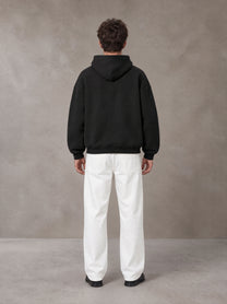 Model wearing SM Sig. Fleece Hoodie in Midnight Black, rear view.