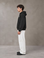 Model wearing SM Sig. Fleece Hoodie in Midnight Black, side profile.