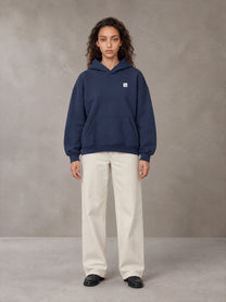 Model wearing SM Sig. Fleece Hoodie in Oxford Navy, front view.