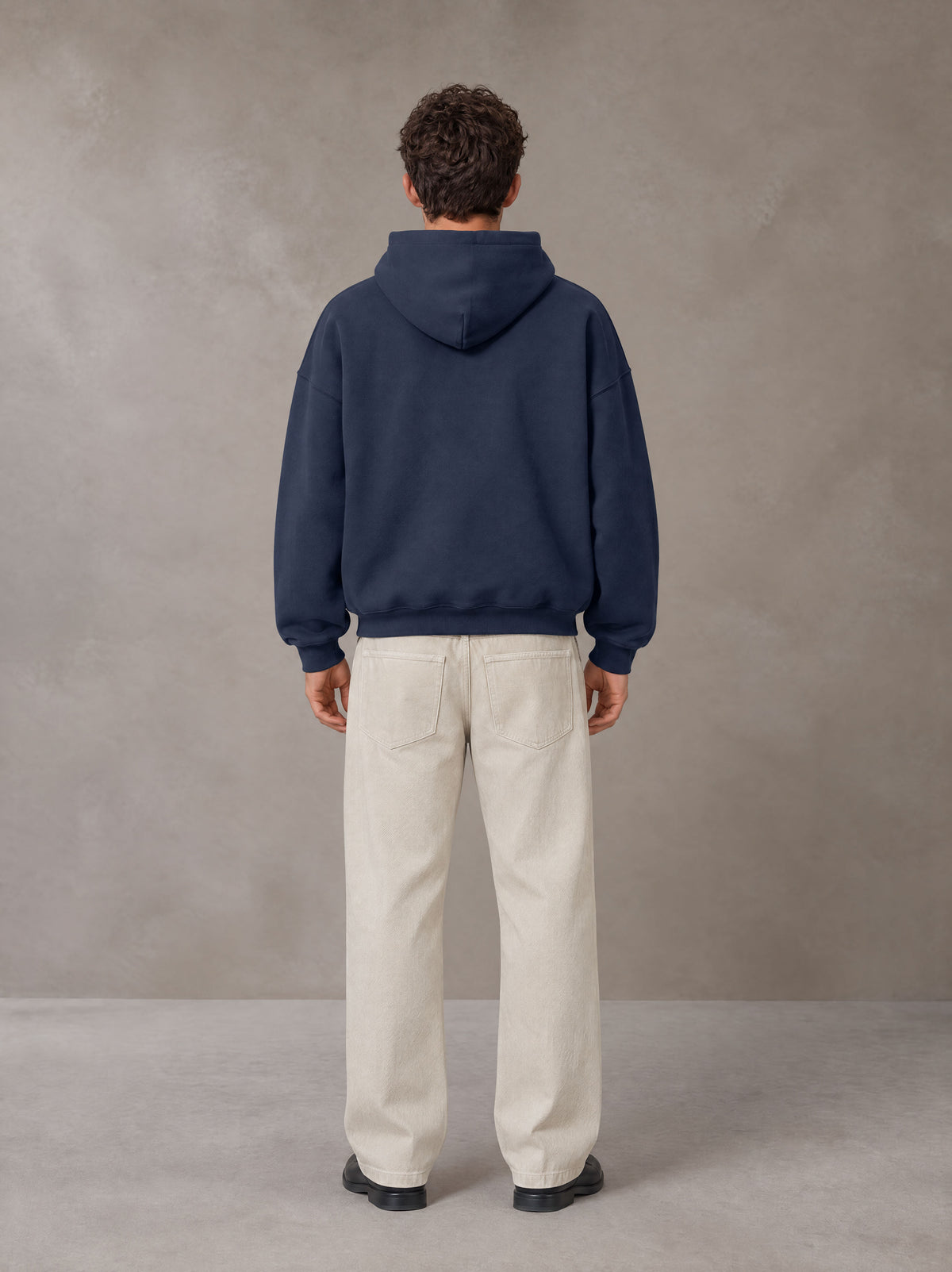 Model wearing SM Sig. Fleece Hoodie in Oxford Navy, rear view.