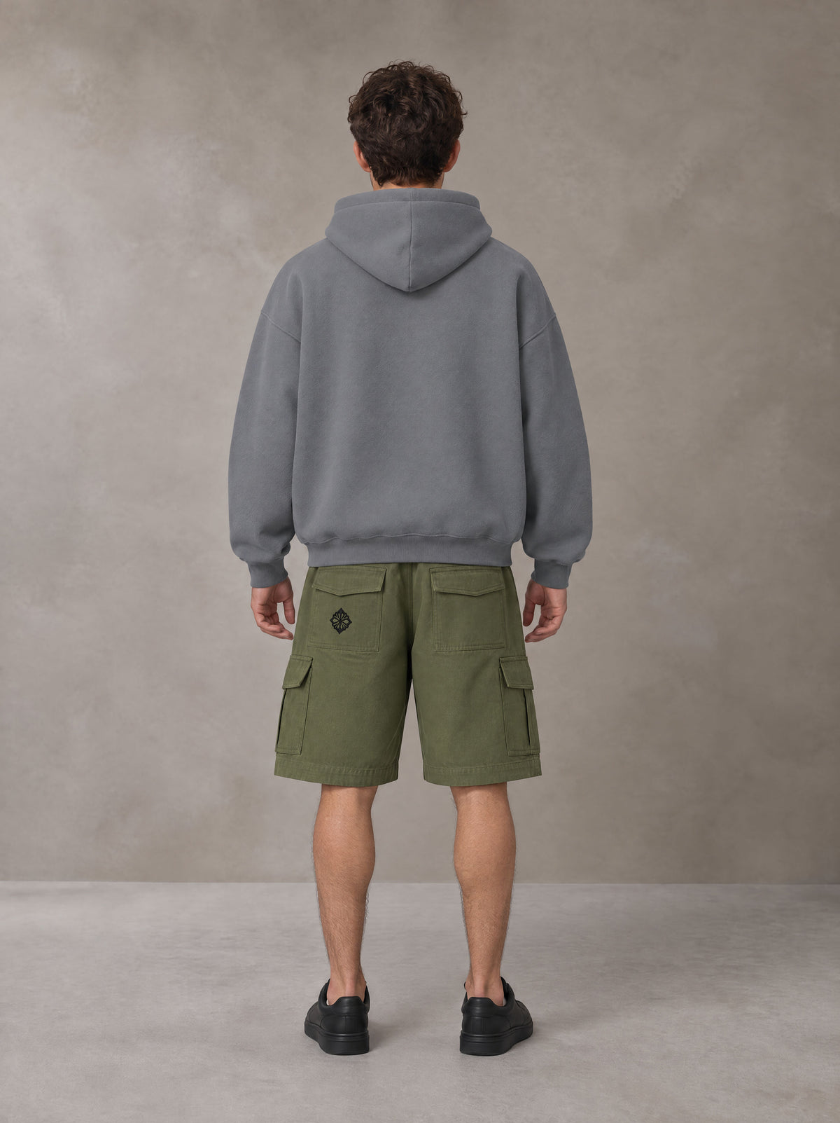 Model wearing SM Sig. Fleece Hoodie in Pure Grey, rear view.