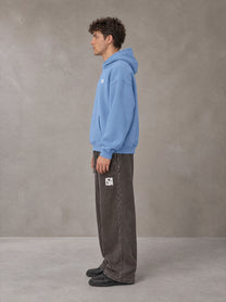 Model wearing SM Sig. Fleece Hoodie in Soft Blue, side profile.