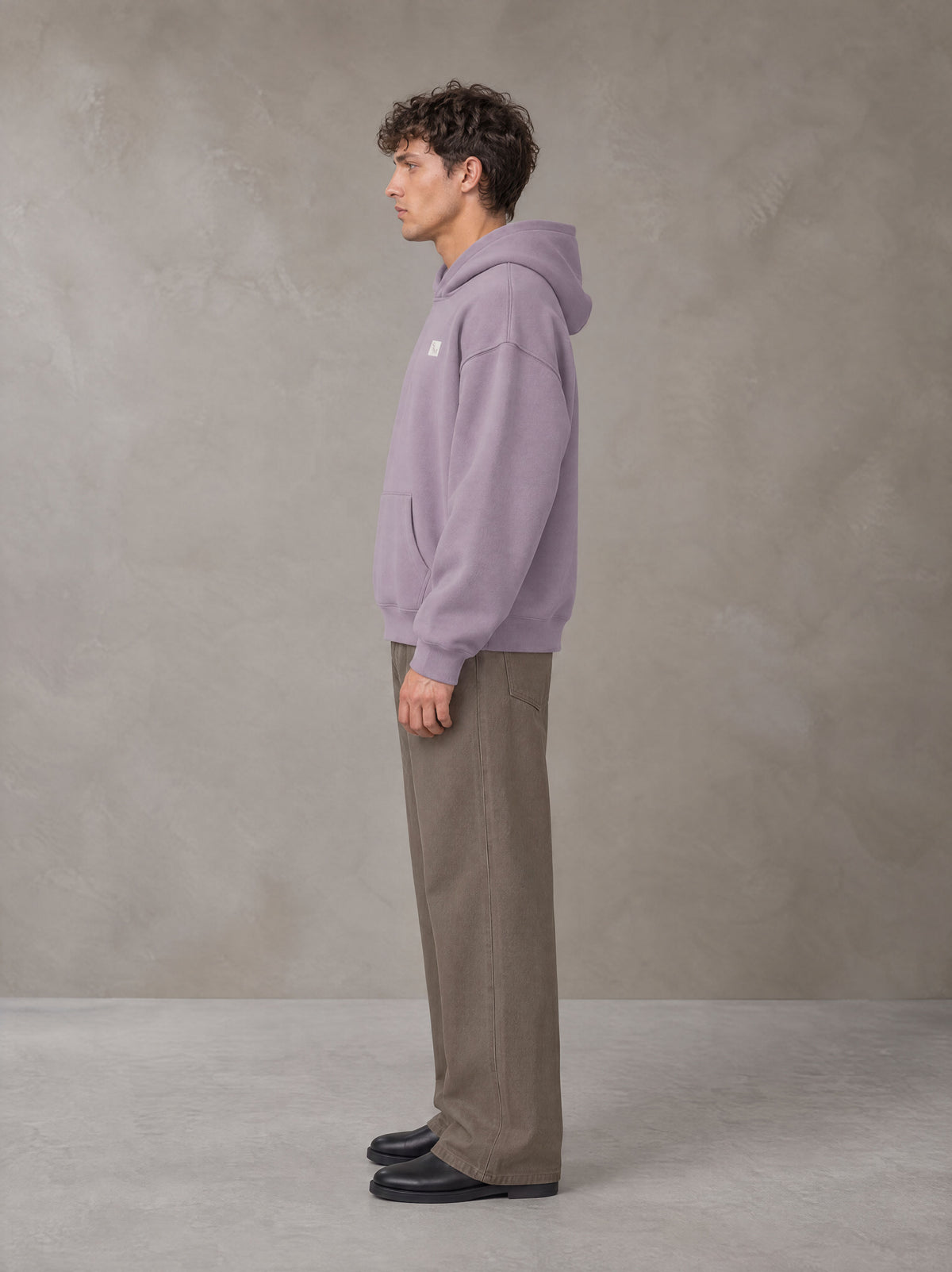 Model wearing SM Sig. Fleece Hoodie in Soft Lavender, side profile.