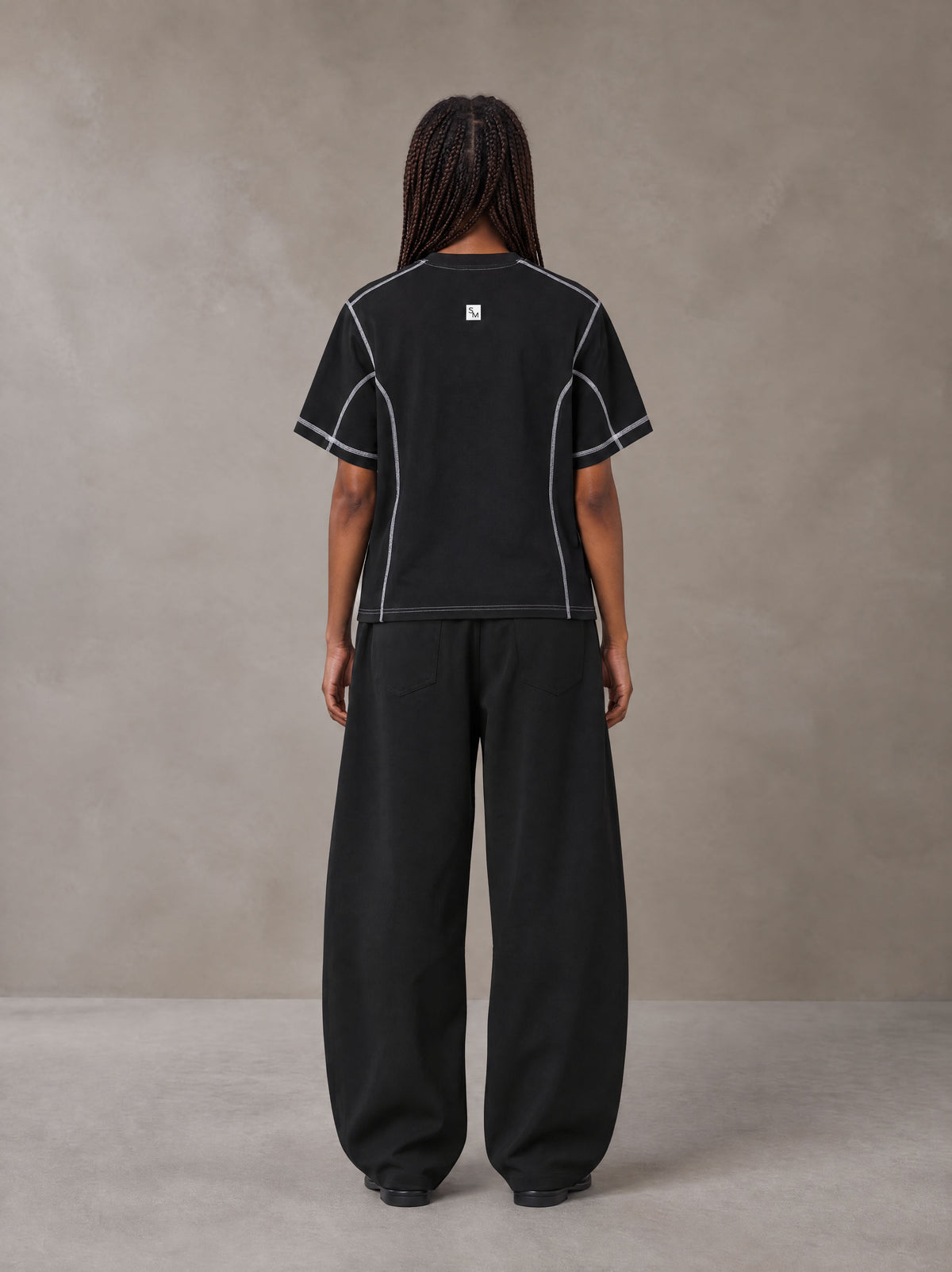 Model wearing SM Sig. Framework T-shirt in Midnight Black, rear view.