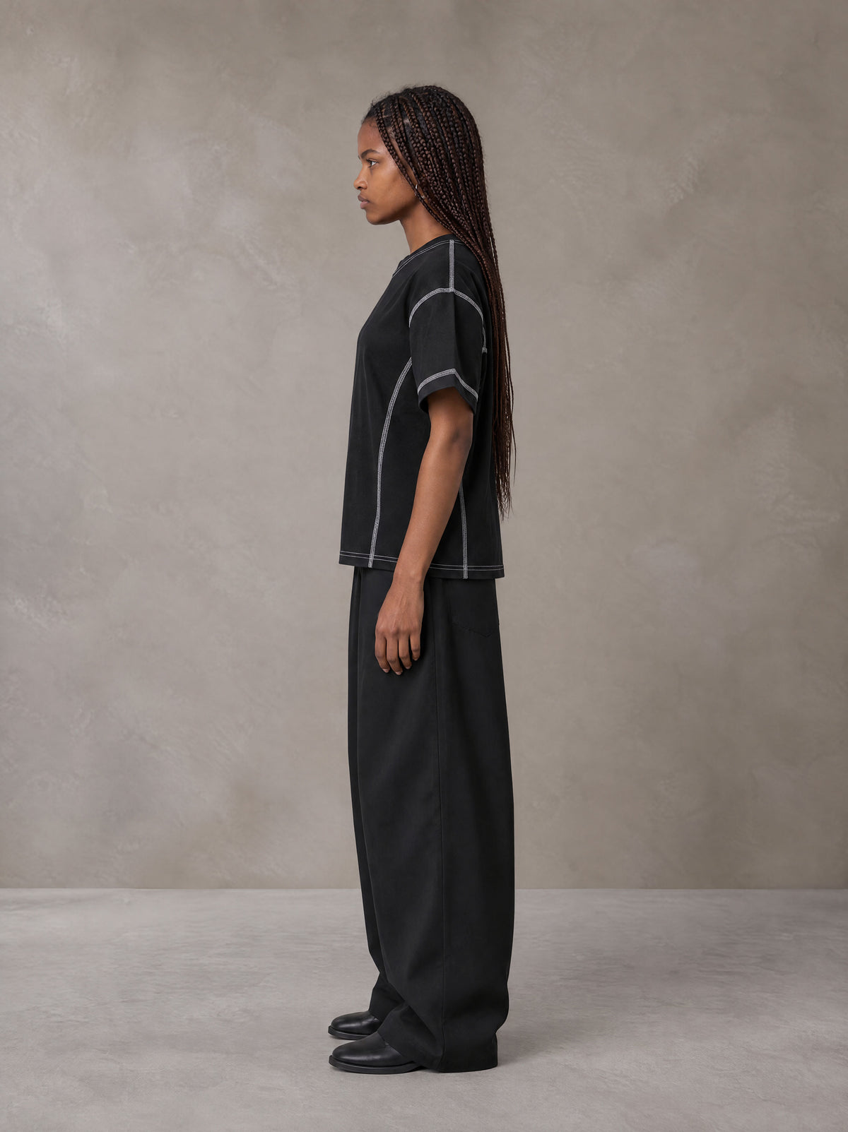 Model wearing SM Sig. Framework T-shirt in Midnight Black, side profile.