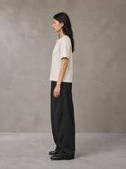 Model wearing SM Sig. Henley T-shirt in Oat Grey, side profile.