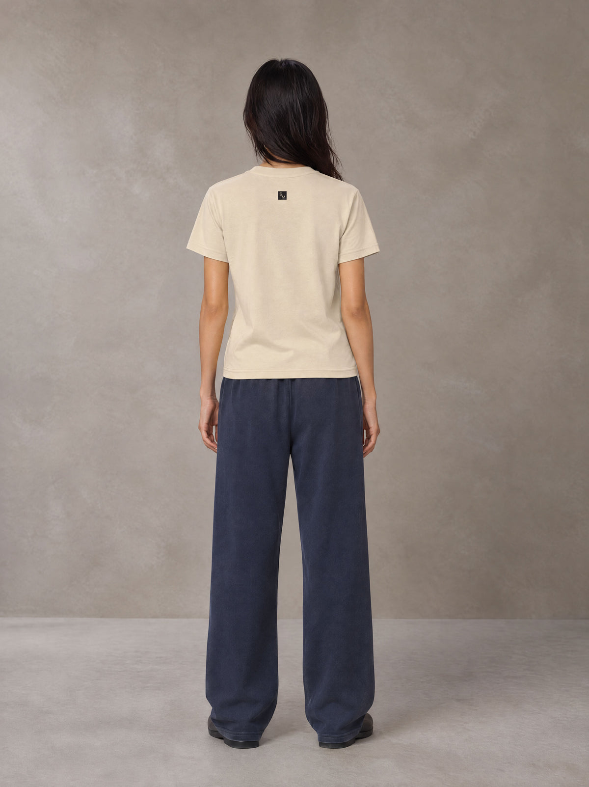 Model wearing SM Sig. Henley T-shirt in Soft Beige, rear view.