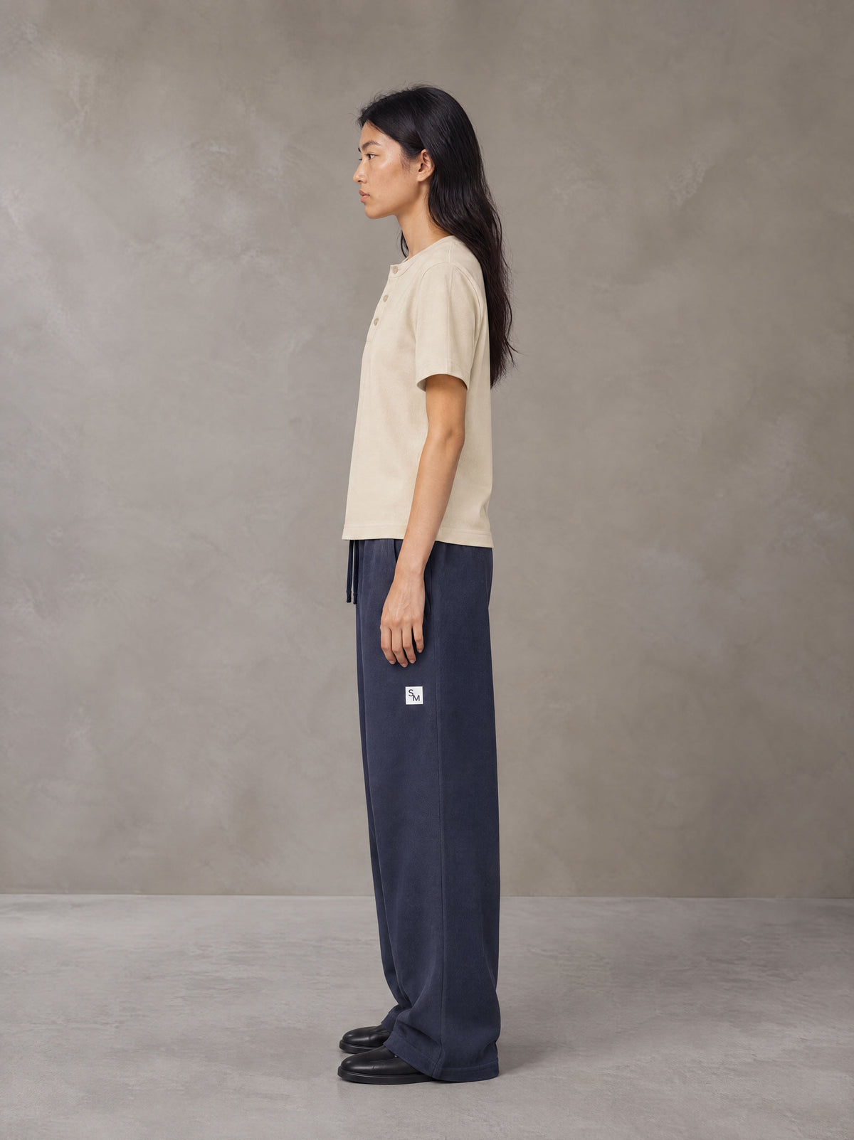 Model wearing SM Sig. Henley T-shirt in Soft Beige, side profile.