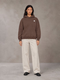 Model wearing SM Sig. High Neck Fleece Hoodie in Brown, front view.