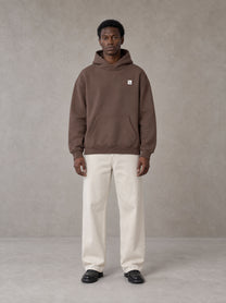 Model wearing SM Sig. High Neck Fleece Hoodie in Brown, front view.