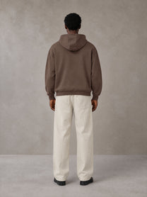 Model wearing SM Sig. High Neck Fleece Hoodie in Brown, rear view.