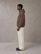 Model wearing SM Sig. High Neck Fleece Hoodie in Brown, side profile.