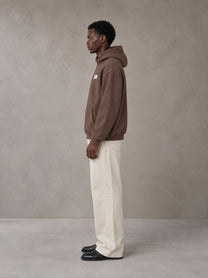 Model wearing SM Sig. High Neck Fleece Hoodie in Brown, side profile.
