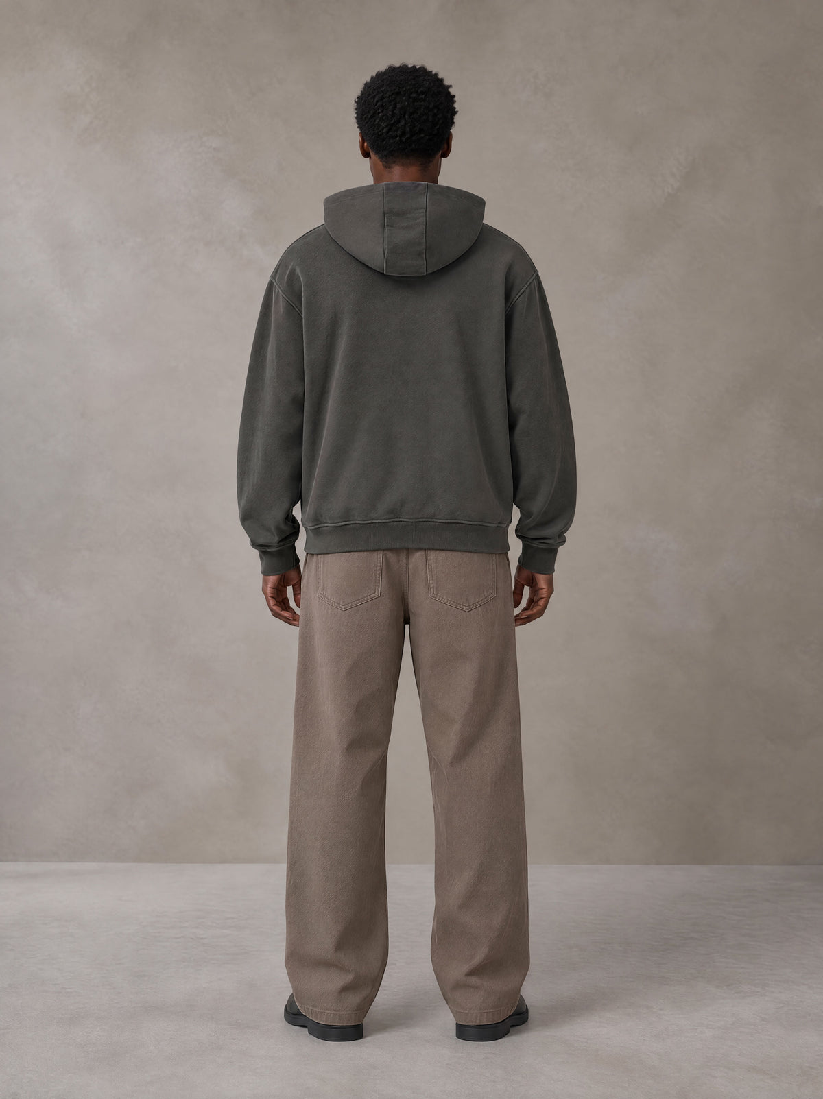 Model wearing SM Sig. High Neck Fleece Hoodie in Deep Charcoal, rear view.