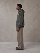 Model wearing SM Sig. High Neck Fleece Hoodie in Deep Charcoal, side profile.