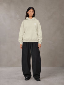 Model wearing SM Sig. High Neck Fleece Hoodie in Fine Sand, front view.
