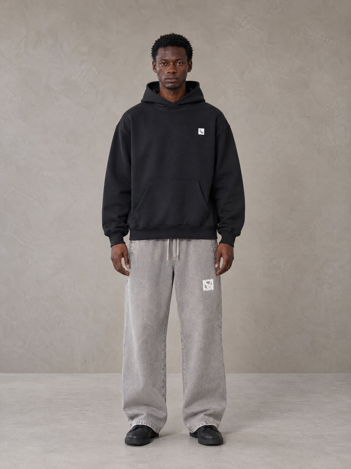 Model wearing SM Sig. High Neck Fleece Hoodie in Midnight Black, front view.