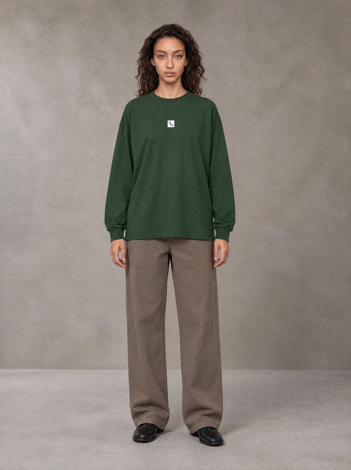 Model wearing SM Sig. Long Sleeve T-shirt in Dark Green, front view.
