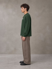 Model wearing SM Sig. Long Sleeve T-shirt in Dark Green, side profile.